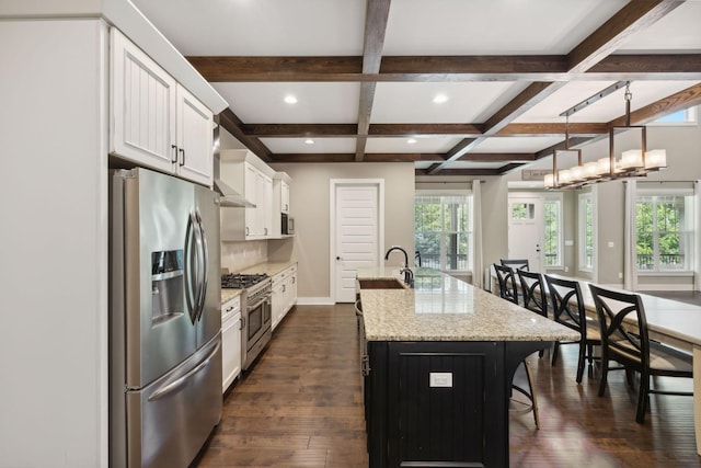 kitchen with white cabinets, light stone counters, decorative light fixtures, a kitchen island with sink, and stainless steel appliances