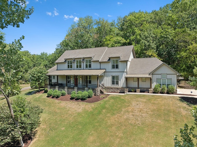 view of front facade with stone siding, a standing seam roof, a porch, and a front yard