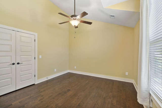 empty room with lofted ceiling, dark wood-style floors, visible vents, and baseboards