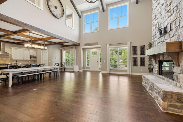 living area featuring dark wood-style flooring, a fireplace, coffered ceiling, beamed ceiling, and baseboards