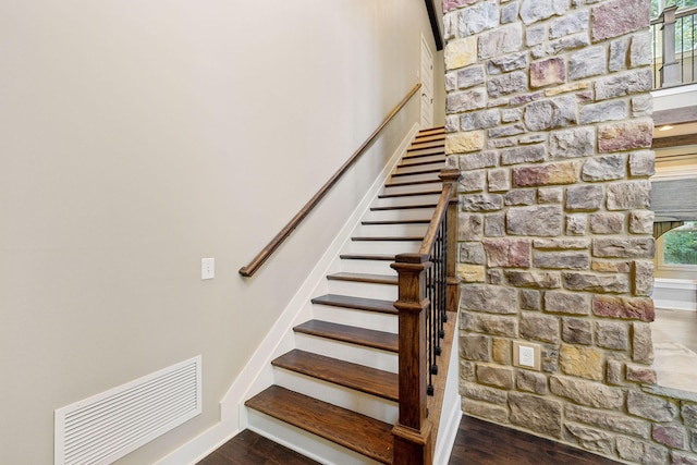 staircase featuring visible vents, baseboards, and wood finished floors