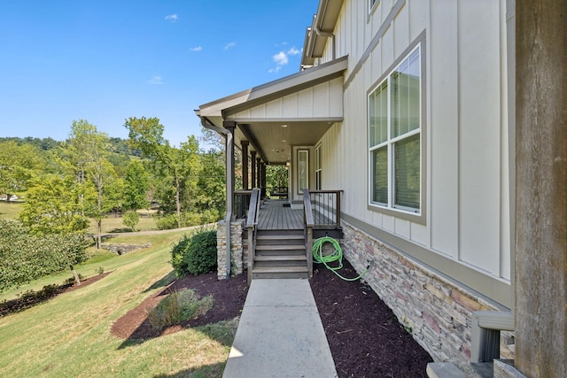 doorway to property featuring a lawn, a porch, and board and batten siding