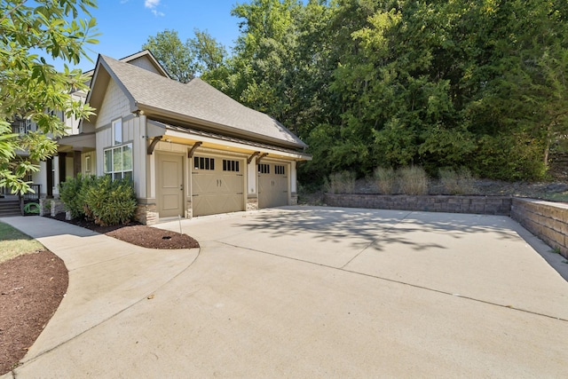 view of home's exterior with a shingled roof, stone siding, driveway, and an attached garage