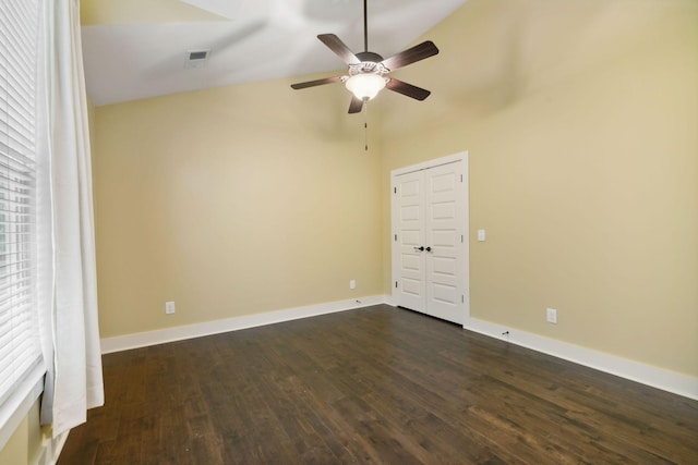 spare room featuring dark wood finished floors, visible vents, vaulted ceiling, ceiling fan, and baseboards