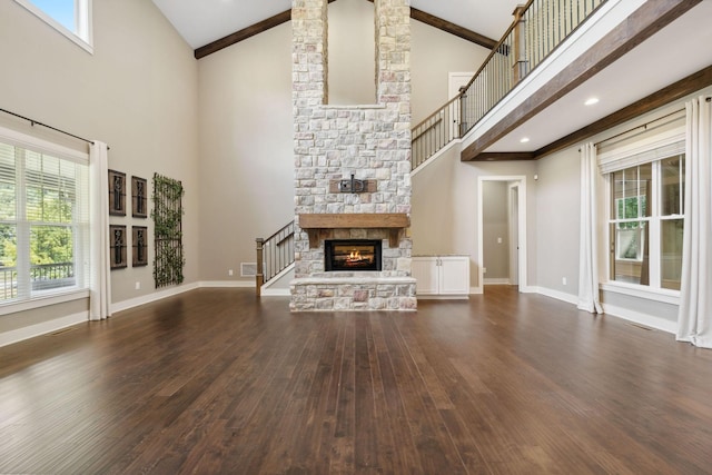 unfurnished living room with dark wood-style flooring, a fireplace, high vaulted ceiling, beamed ceiling, and baseboards