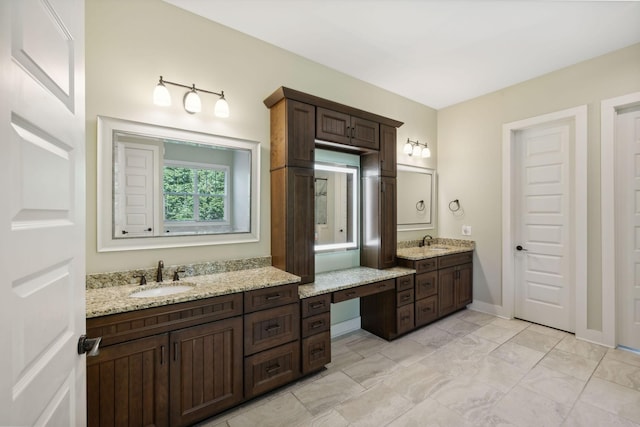 bathroom featuring two vanities, a sink, and baseboards