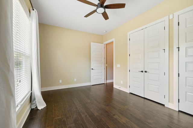 unfurnished bedroom with dark wood-style flooring, a closet, a ceiling fan, and baseboards