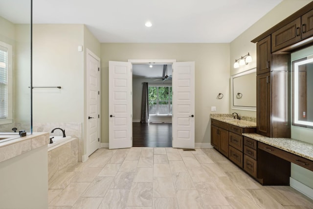 full bathroom with a ceiling fan, vanity, baseboards, and a bath