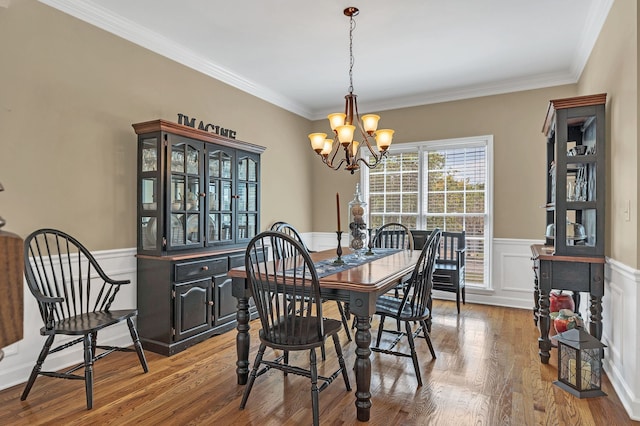 dining room featuring wood-type flooring, ornamental molding, and a chandelier