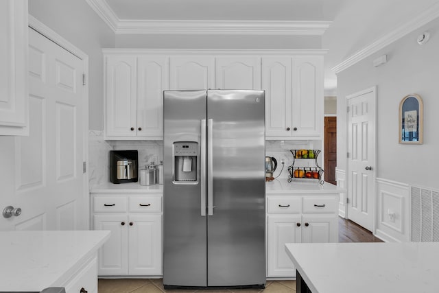 kitchen with stainless steel fridge with ice dispenser, backsplash, ornamental molding, and white cabinetry