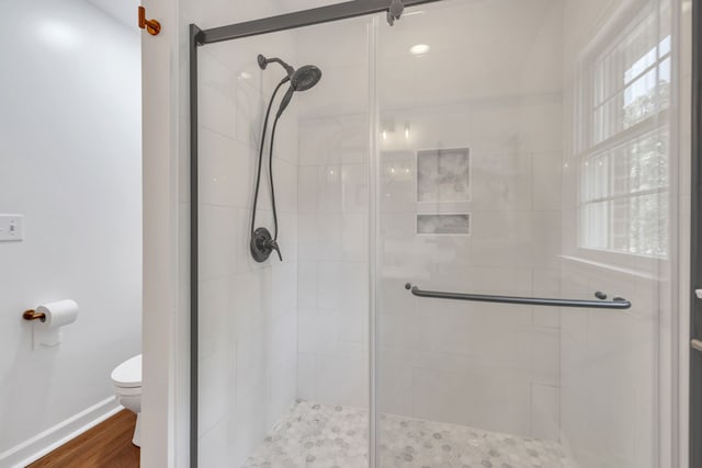 bathroom with wood-type flooring, toilet, and an enclosed shower