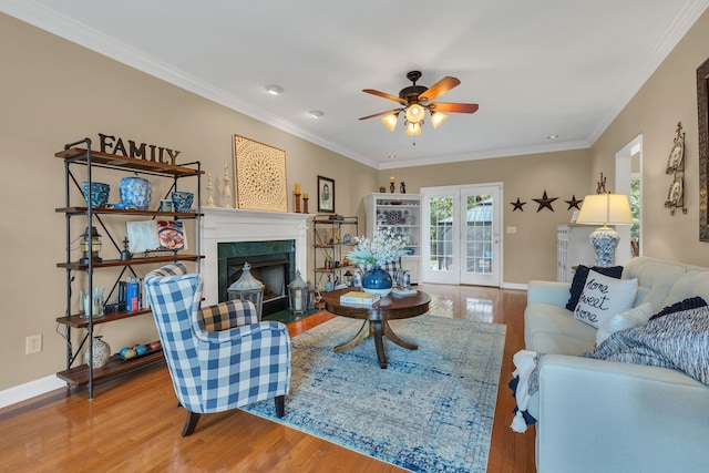 living room with hardwood / wood-style floors, crown molding, a tile fireplace, and ceiling fan