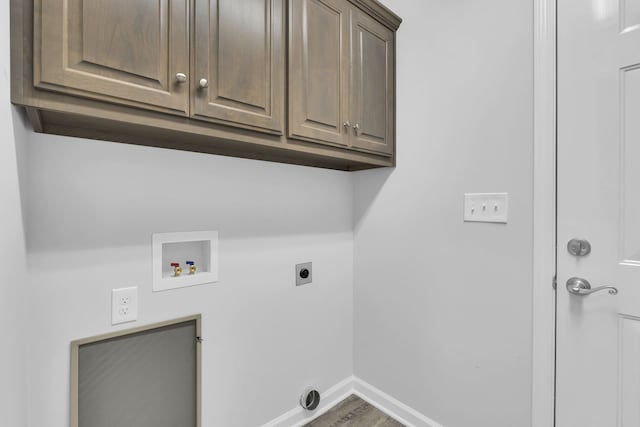 clothes washing area featuring hardwood / wood-style floors, hookup for a washing machine, electric dryer hookup, and cabinets