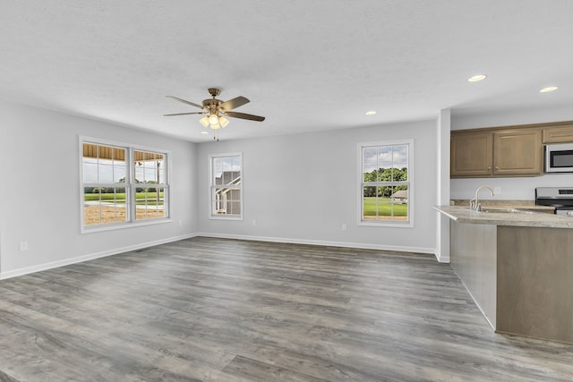 unfurnished living room with sink, plenty of natural light, ceiling fan, and hardwood / wood-style floors