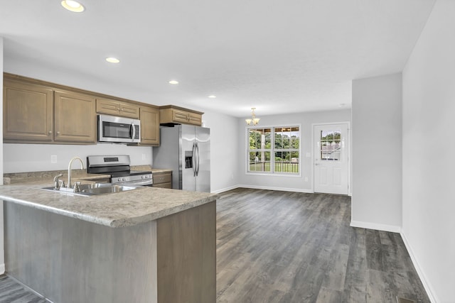 kitchen with sink, decorative light fixtures, appliances with stainless steel finishes, dark hardwood / wood-style floors, and kitchen peninsula