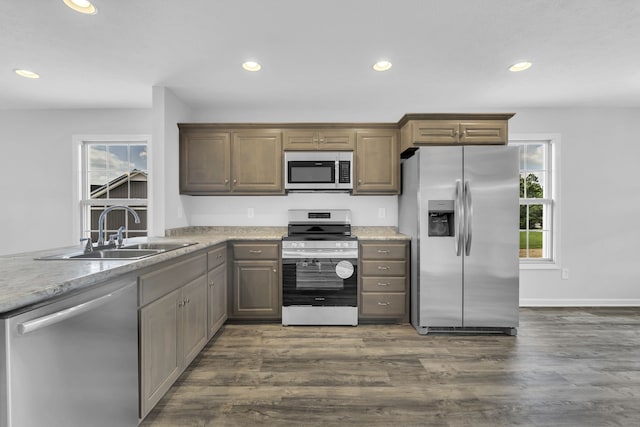 kitchen featuring appliances with stainless steel finishes, hardwood / wood-style floors, sink, and light stone countertops