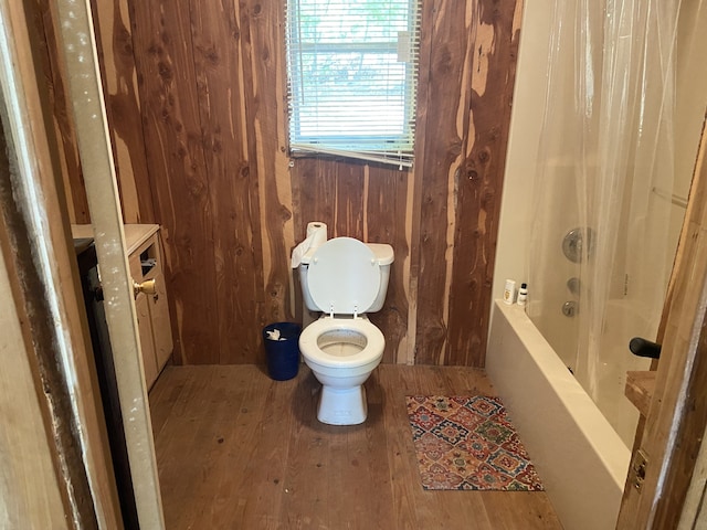 bathroom with wood walls, hardwood / wood-style floors, shower / tub combo, and toilet