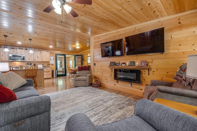 living room featuring light wood-type flooring, ceiling fan, wooden ceiling, and wooden walls