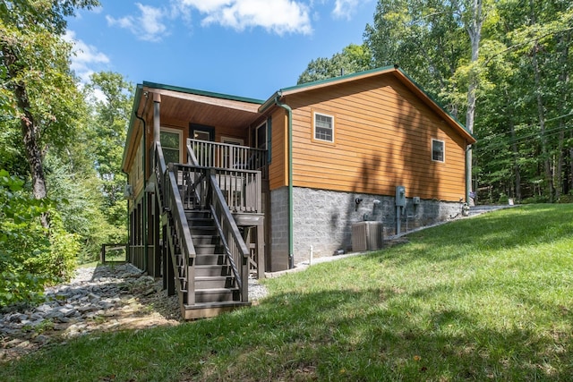 rear view of property featuring central air condition unit and a lawn