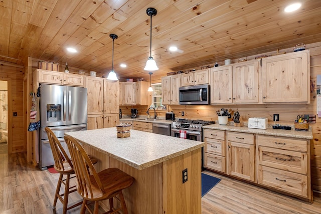 kitchen featuring a kitchen island, stainless steel appliances, light brown cabinetry, and pendant lighting