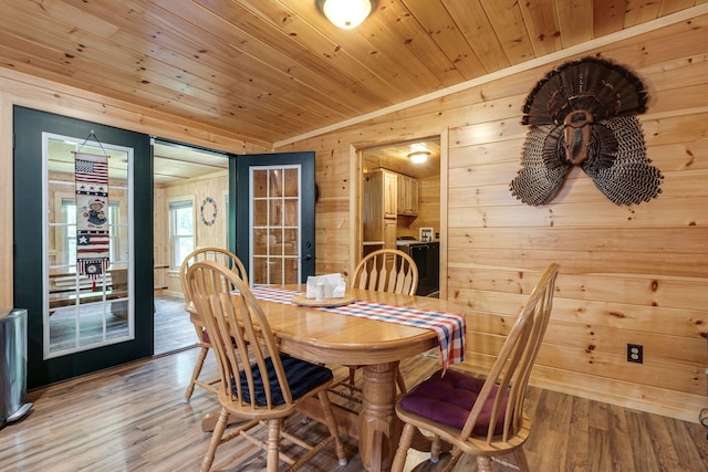 dining room with light wood-type flooring, wooden walls, and wood ceiling