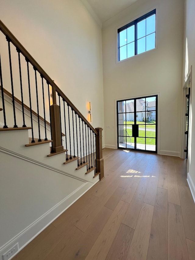 entryway featuring stairway, baseboards, wood finished floors, and a towering ceiling