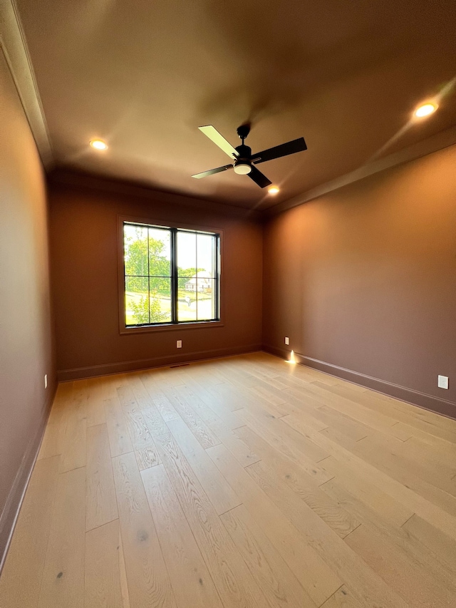 spare room with crown molding, ceiling fan, and light wood-type flooring