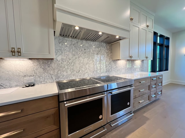 kitchen featuring custom exhaust hood, tasteful backsplash, white cabinetry, and electric stove