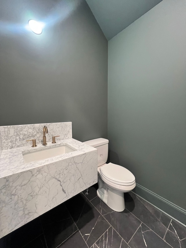 bathroom featuring lofted ceiling, sink, and toilet