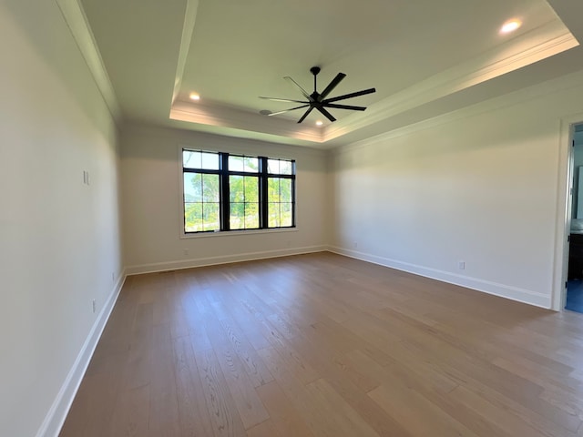 spare room with hardwood / wood-style flooring, ornamental molding, ceiling fan, and a tray ceiling