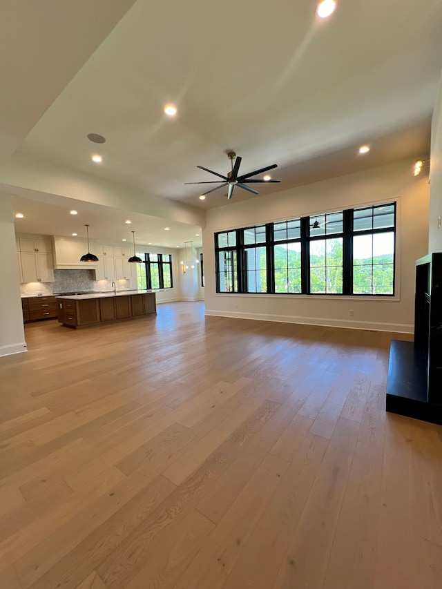 unfurnished living room featuring ceiling fan and light hardwood / wood-style floors