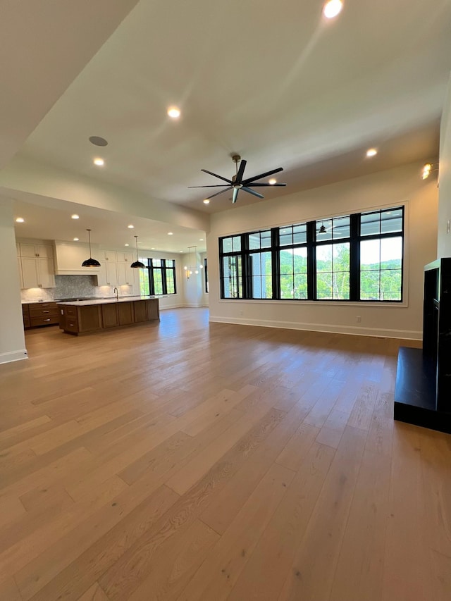 unfurnished living room with recessed lighting, baseboards, and light wood finished floors