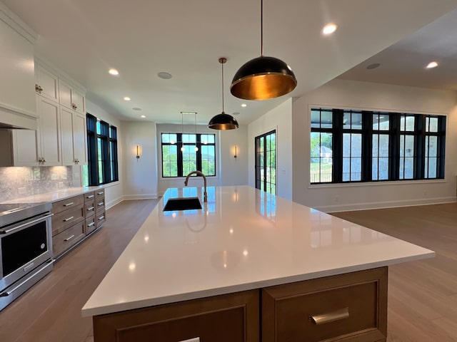 kitchen featuring a large island, sink, hanging light fixtures, white cabinets, and stainless steel electric range oven