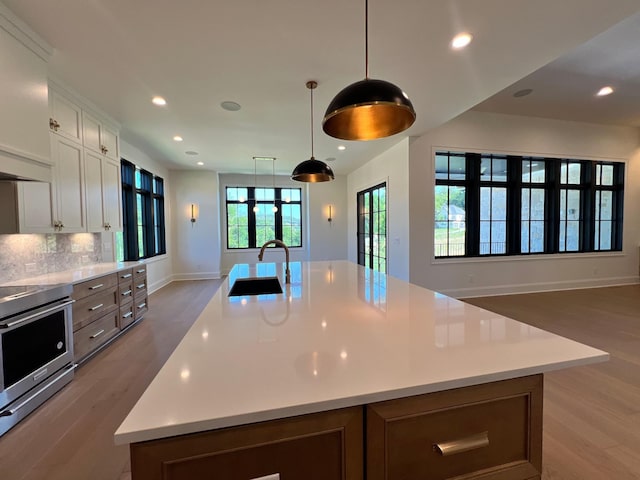 kitchen featuring light wood-type flooring, a sink, light countertops, stainless steel range with electric stovetop, and open floor plan