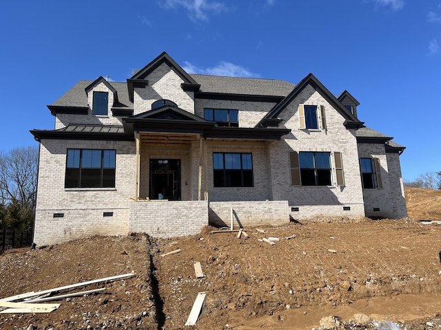 view of front facade with a standing seam roof, brick siding, and crawl space