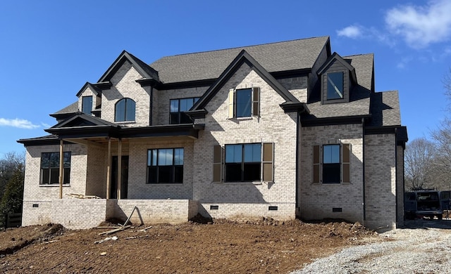 view of front facade with crawl space, brick siding, and roof with shingles