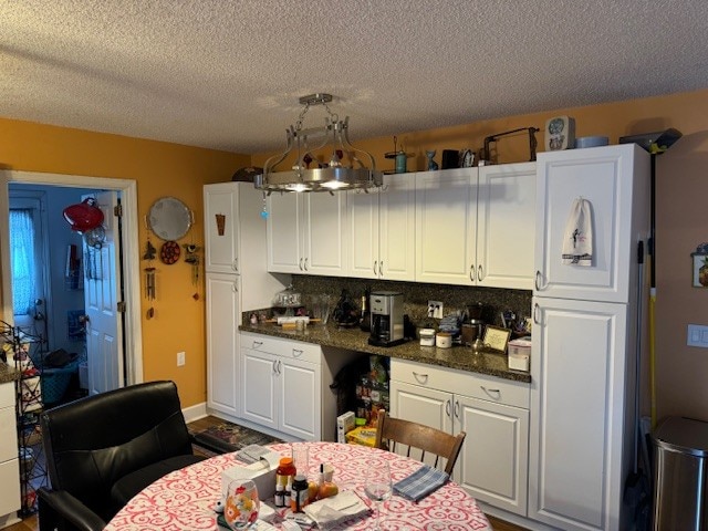 kitchen featuring white cabinets, tasteful backsplash, and a textured ceiling