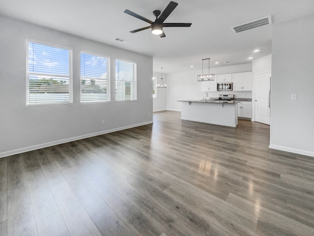 unfurnished living room featuring sink, ceiling fan with notable chandelier, and wood-type flooring