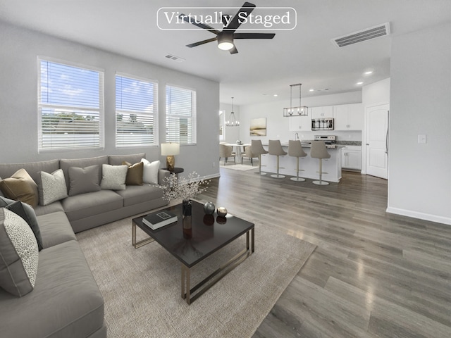 living room featuring ceiling fan with notable chandelier and wood-type flooring