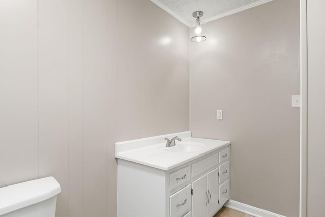 bathroom with ornamental molding, baseboards, vanity, and toilet