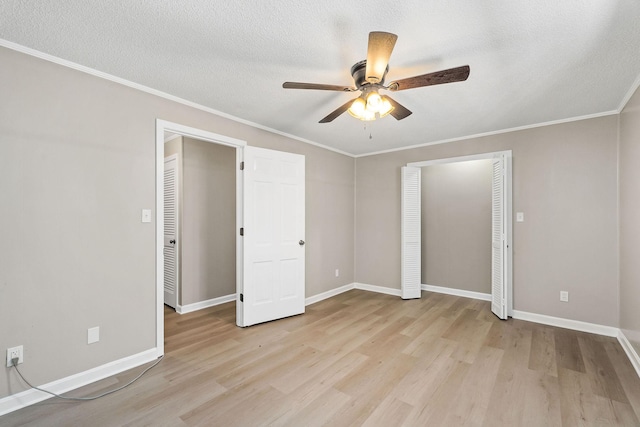 unfurnished bedroom with baseboards, a textured ceiling, light wood-style flooring, and crown molding