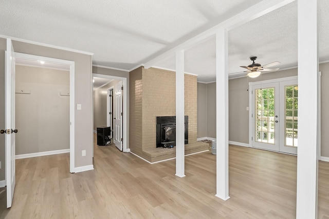 unfurnished living room featuring baseboards, french doors, a textured ceiling, crown molding, and light wood-type flooring