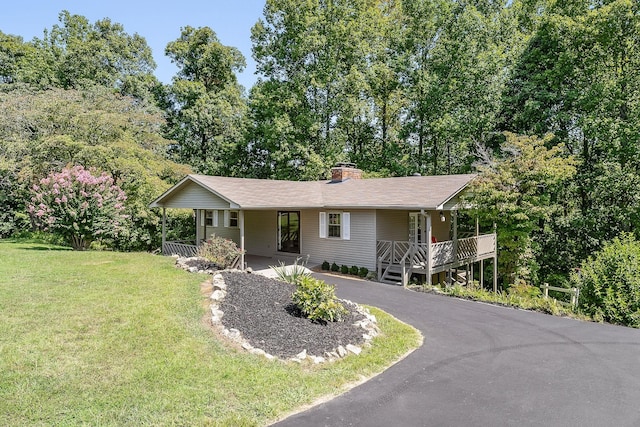 single story home featuring covered porch, aphalt driveway, a chimney, and a front yard