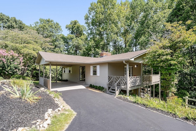 ranch-style house featuring driveway, a chimney, and an attached carport