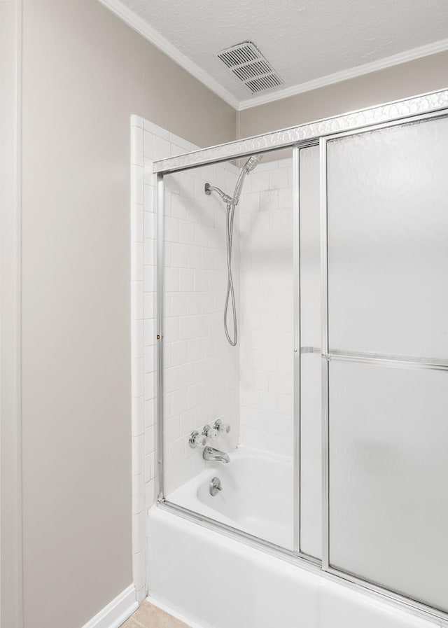 bathroom featuring a textured ceiling, shower / bath combination with glass door, visible vents, and crown molding