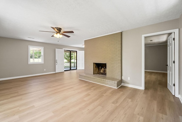 unfurnished living room featuring baseboards, a ceiling fan, light wood-style floors, a textured ceiling, and a brick fireplace