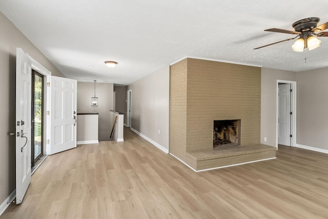 foyer featuring a brick fireplace, baseboards, a textured ceiling, and light wood finished floors