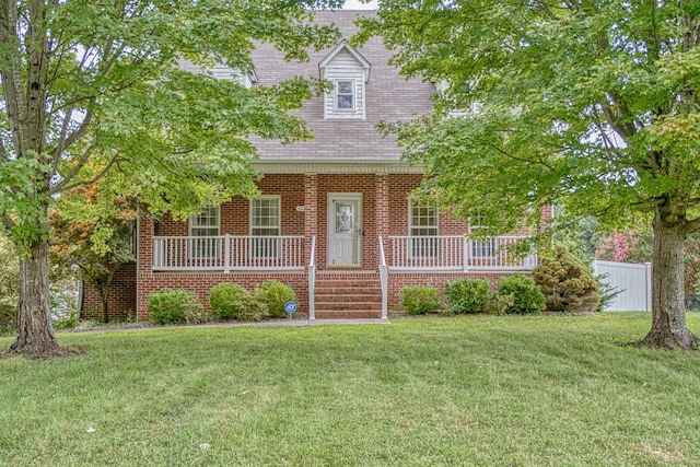 new england style home featuring covered porch, brick siding, and a front yard