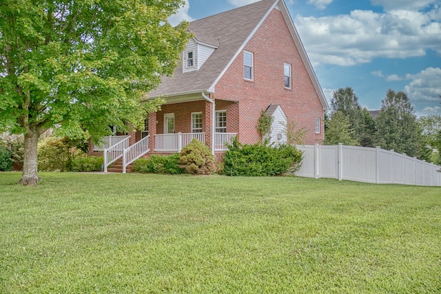 new england style home featuring a front yard and covered porch