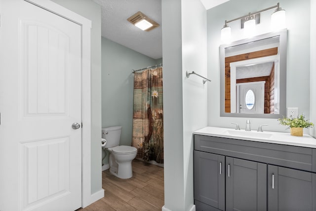 bathroom featuring wood-type flooring, toilet, a textured ceiling, and vanity